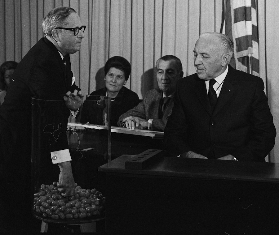 Figure 2.5: Congressman Alexander Pirnie (R-NY) drawing the first capsule for the Selective Service draft on December 1, 1969. Joshua Angrist (1990) combined the draft lottery with earnings data from the Social Security Administration to estimate the effect of military service on earnings. This is an example of research using a natural experiment. Source: Wikimedia Commons